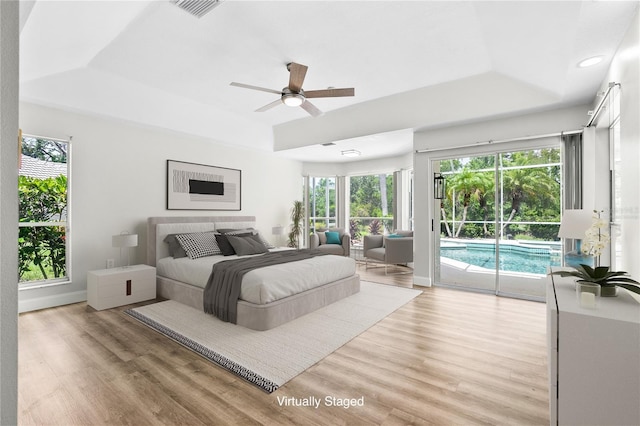 4724 White Tail Ln, Sarasota, FL 34238 - bedroom with a raised ceiling, access to outside, light wood-type flooring, multiple windows, and recessed lighting