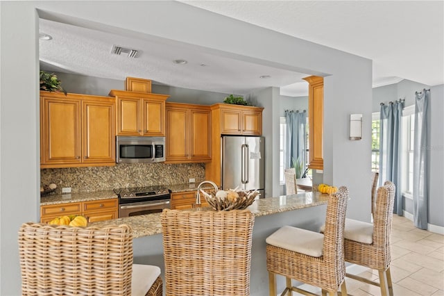 7611 34th Ave W Unit 301, Bradenton, FL 34209 - kitchen with stainless steel appliances, decorative backsplash, a kitchen breakfast bar, and light tile patterned floors