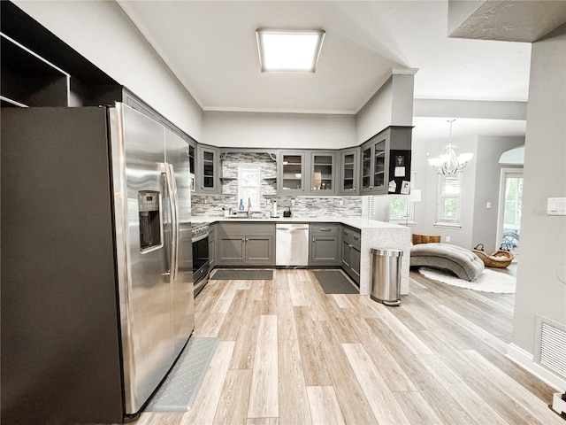 25640 State Road 70 E, Myakka City, FL 34251 - kitchen featuring appliances with stainless steel finishes, gray cabinetry, tasteful backsplash, light countertops, and glass insert cabinets