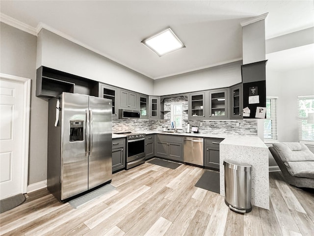 25640 State Road 70 E, Myakka City, FL 34251 - kitchen with appliances with stainless steel finishes, gray cabinets, decorative backsplash, glass insert cabinets, and crown molding