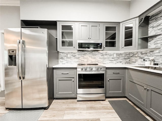 25640 State Road 70 E, Myakka City, FL 34251 - kitchen with stainless steel appliances, gray cabinets, light wood-type flooring, and tasteful backsplash