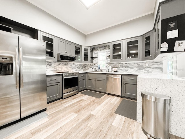25640 State Road 70 E, Myakka City, FL 34251 - kitchen featuring stainless steel appliances, gray cabinets, decorative backsplash, light wood finished floors, and crown molding