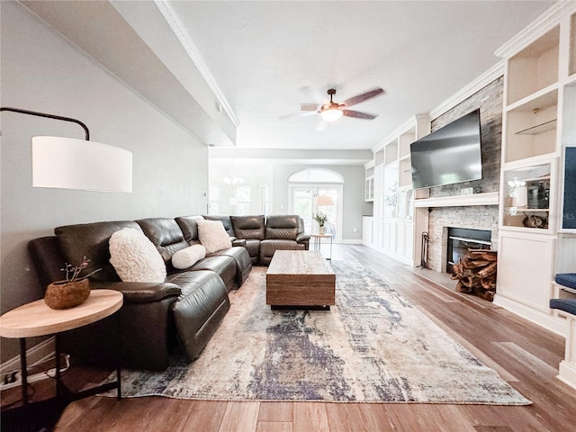 25640 State Road 70 E, Myakka City, FL 34251 - living room featuring ceiling fan, wood finished floors, a stone fireplace, built in shelves, and ornamental molding