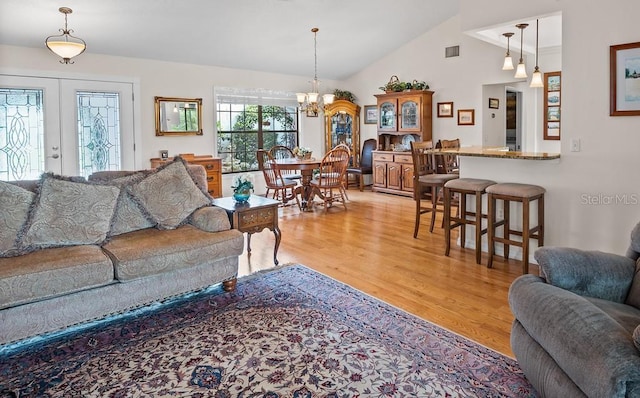 8703 53rd Ave W, Bradenton, FL 34210 - living room with light wood-type flooring, vaulted ceiling, a chandelier, and french doors