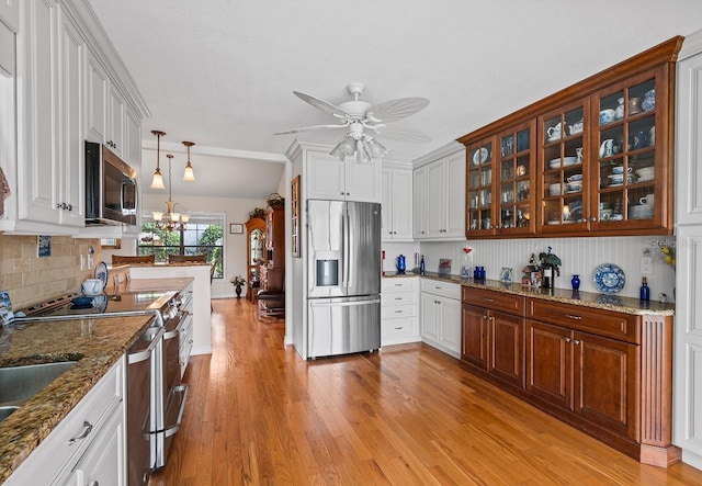 8703 53rd Ave W, Bradenton, FL 34210 - kitchen featuring stainless steel appliances, light wood-style flooring, ceiling fan, glass insert cabinets, and white cabinets