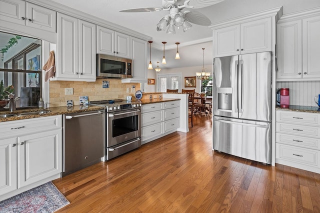 8703 53rd Ave W, Bradenton, FL 34210 - kitchen with appliances with stainless steel finishes, light wood finished floors, ceiling fan, decorative backsplash, and dark stone counters