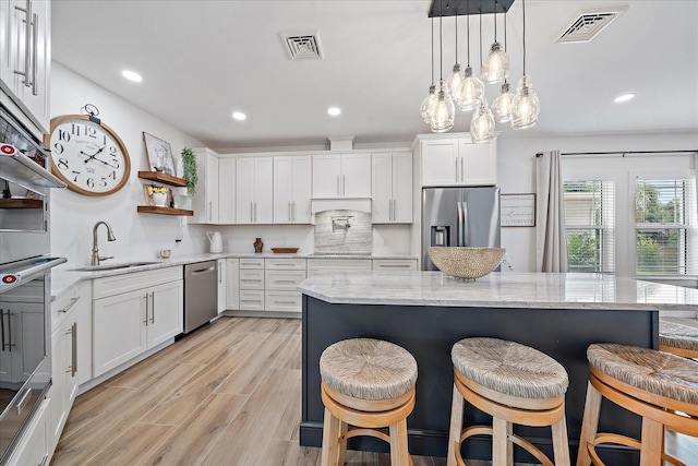 1876 Livingstone St, Sarasota, FL 34231 - kitchen featuring stainless steel appliances, white cabinetry, a breakfast bar area, recessed lighting, and open shelves