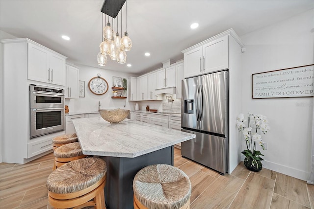 1876 Livingstone St, Sarasota, FL 34231 - kitchen with stainless steel appliances, recessed lighting, white cabinets, light stone counters, and a kitchen breakfast bar