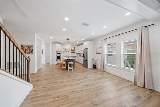 1876 Livingstone St, Sarasota, FL 34231 - kitchen with appliances with stainless steel finishes, white cabinetry, a kitchen breakfast bar, a center island, and light countertops