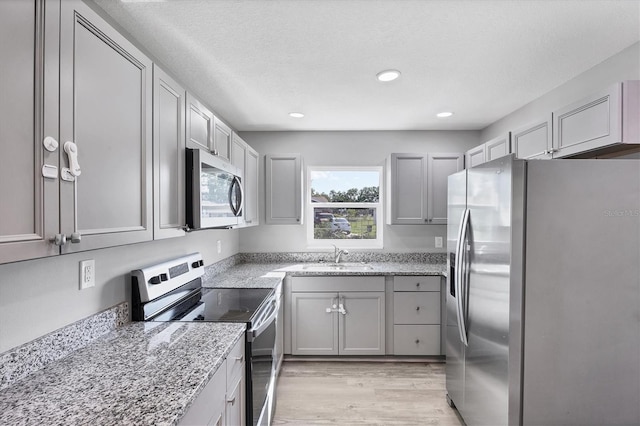 3327 King Blvd, Sarasota, FL 34234 - kitchen featuring stainless steel appliances, light wood-type flooring, light stone counters, recessed lighting, and a textured ceiling