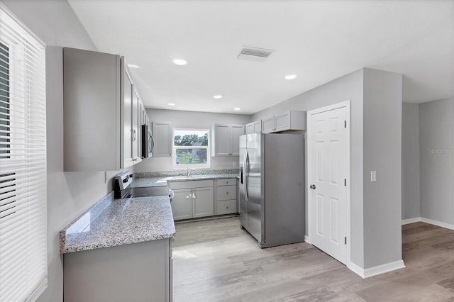 3327 King Blvd, Sarasota, FL 34234 - kitchen featuring appliances with stainless steel finishes, gray cabinets, light wood-type flooring, light stone countertops, and recessed lighting
