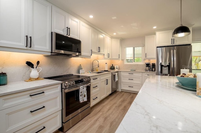 1801 Gulf Dr N Unit 276, Bradenton Beach, FL 34217 - kitchen featuring appliances with stainless steel finishes, white cabinets, light wood finished floors, light stone countertops, and recessed lighting