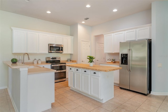 5405 98th Ave E, Parrish, FL 34219 - kitchen featuring appliances with stainless steel finishes, white cabinets, a peninsula, a kitchen island, and light tile patterned floors