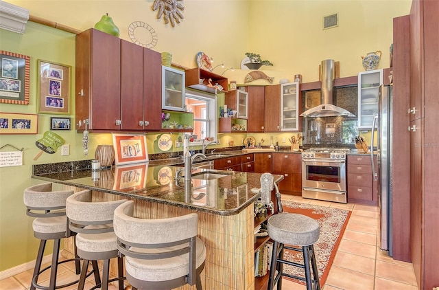 701 Marbury Ln, Longboat Key, FL 34228 - kitchen with stainless steel appliances, wall chimney range hood, a peninsula, and light tile patterned floors