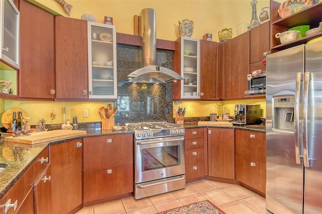 701 Marbury Ln, Longboat Key, FL 34228 - kitchen with appliances with stainless steel finishes, wall chimney exhaust hood, light tile patterned floors, dark stone countertops, and glass insert cabinets