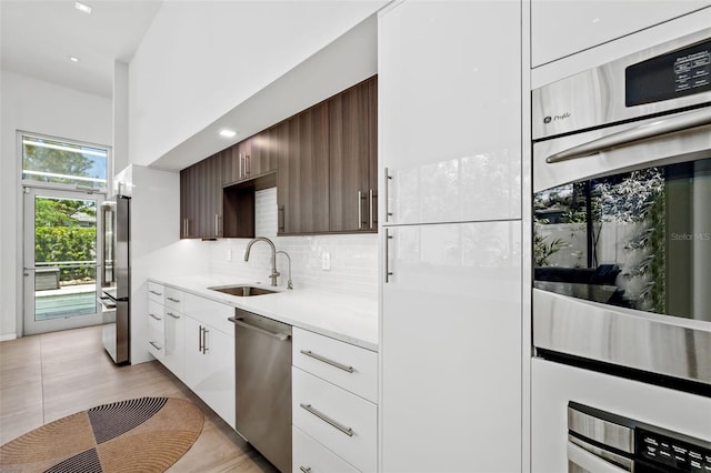 904 Virginia Dr, Sarasota, FL 34234 - kitchen featuring stainless steel appliances, light countertops, decorative backsplash, white cabinets, and dark brown cabinets