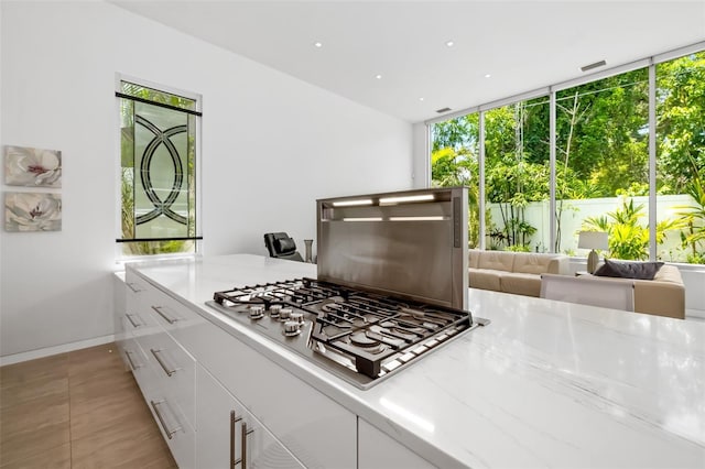 904 Virginia Dr, Sarasota, FL 34234 - kitchen with stainless steel gas cooktop, plenty of natural light, white cabinets, recessed lighting, and light tile patterned flooring