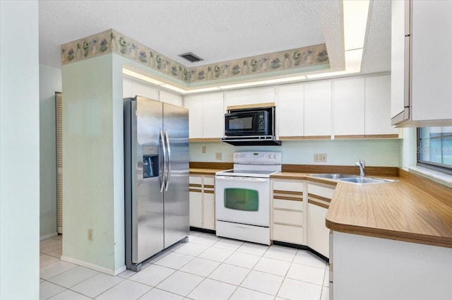 2708 Wilkinson Rd, Sarasota, FL 34231 - kitchen featuring stainless steel fridge, black microwave, electric range, white cabinetry, and light tile patterned floors