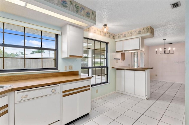 2708 Wilkinson Rd, Sarasota, FL 34231 - kitchen with dishwasher, light tile patterned floors, white cabinetry, a chandelier, and a textured ceiling