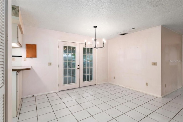 2708 Wilkinson Rd, Sarasota, FL 34231 - unfurnished dining area with a chandelier, a textured ceiling, light tile patterned floors, and french doors