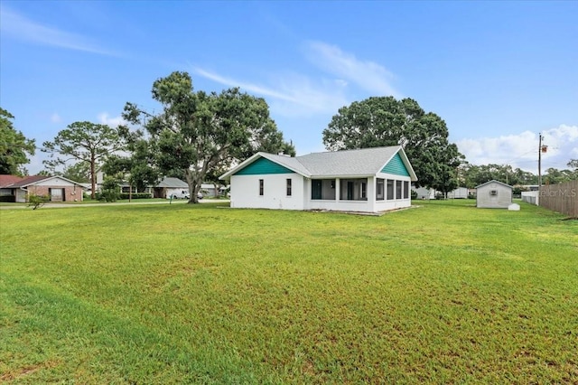 2708 Wilkinson Rd, Sarasota, FL 34231 - back of house with a lawn, a sunroom, a storage shed, and roof with shingles