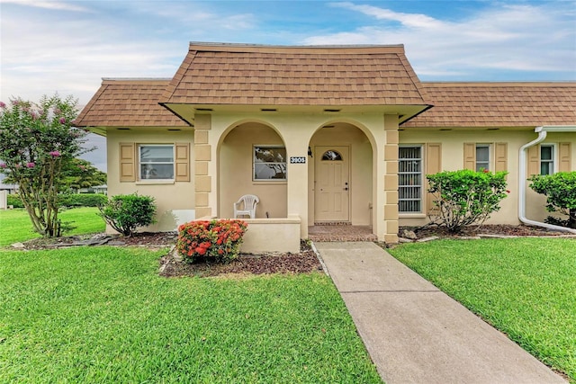 3905 34th Avenue Dr W Unit 36, Bradenton, FL 34205 - view of front of home with mansard roof, roof with shingles, stucco siding, and a front yard