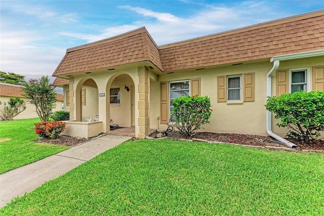 3905 34th Avenue Dr W Unit 36, Bradenton, FL 34205 - view of front of house featuring roof with shingles, mansard roof, stucco siding, and a front yard