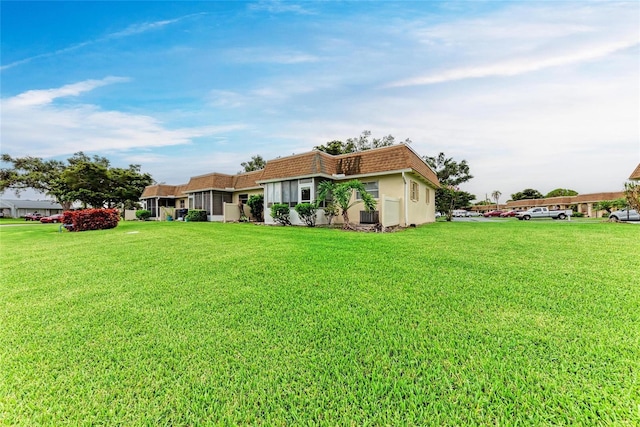 3905 34th Avenue Dr W Unit 36, Bradenton, FL 34205 - back of property featuring mansard roof, a lawn, and stucco siding