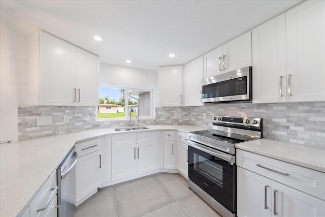 3959 Coleridge Pl, Sarasota, FL 34241 - kitchen featuring appliances with stainless steel finishes, light tile patterned floors, white cabinets, backsplash, and recessed lighting