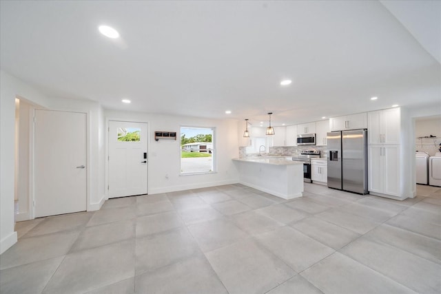 3959 Coleridge Pl, Sarasota, FL 34241 - kitchen featuring stainless steel appliances, independent washer and dryer, a peninsula, light countertops, and white cabinetry