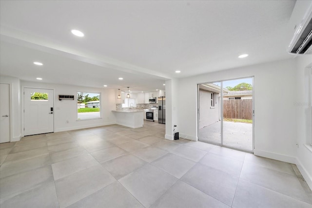 3959 Coleridge Pl, Sarasota, FL 34241 - unfurnished living room featuring recessed lighting, plenty of natural light, a wall mounted air conditioner, and light tile patterned floors