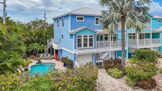 202 75th St, Holmes Beach, FL 34217 - back of house with an attached garage, stairway, and an outdoor pool