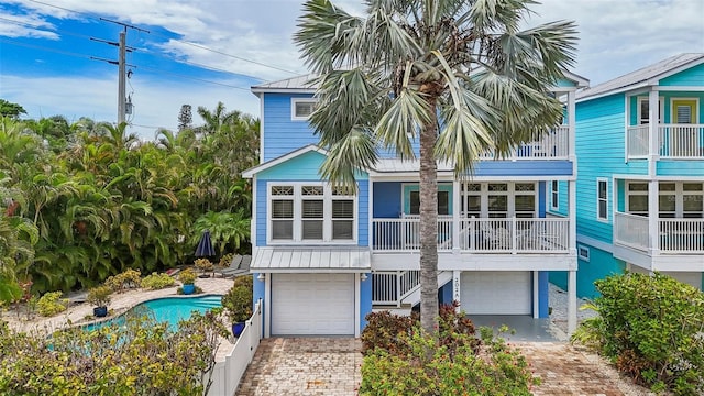 202 75th St, Holmes Beach, FL 34217 - back of property featuring decorative driveway, a garage, and a metal roof