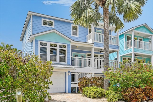 202 75th St, Holmes Beach, FL 34217 - back of property with ceiling fan, an attached garage, a balcony, stairs, and driveway
