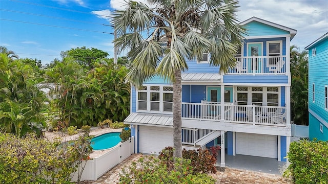 202 75th St, Holmes Beach, FL 34217 - rear view of house with an attached garage, stairway, a balcony, covered porch, and driveway