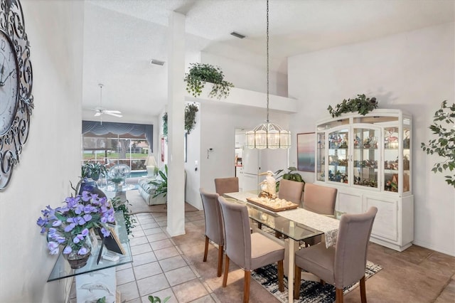 5766 Beaurivage Ave, Sarasota, FL 34243 - dining room with ceiling fan, a chandelier, high vaulted ceiling, light tile patterned flooring, and a textured ceiling