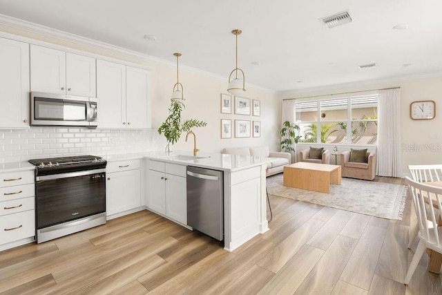 12017 Cranston Way, Bradenton, FL 34211 - kitchen featuring appliances with stainless steel finishes, light wood finished floors, light countertops, open floor plan, and ornamental molding