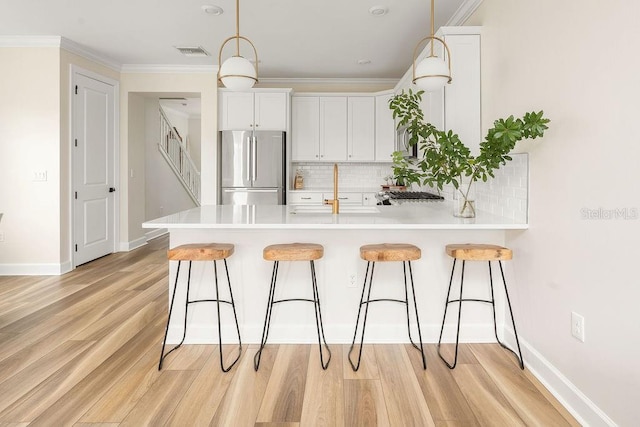 12017 Cranston Way, Bradenton, FL 34211 - kitchen featuring stainless steel fridge, a peninsula, a breakfast bar area, tasteful backsplash, and ornamental molding