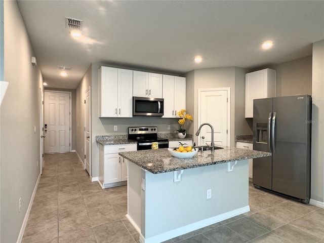 5812 Ocean Isle Dr, Nokomis, FL 34275 - kitchen with stainless steel appliances, dark stone counters, white cabinets, a kitchen bar, and a kitchen island with sink