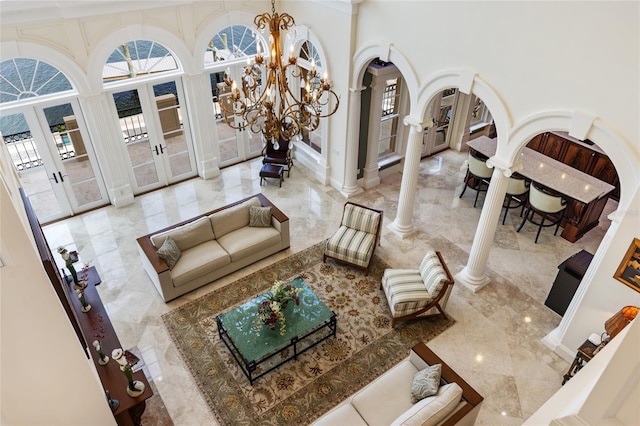 309 Ringling Point Dr, Sarasota, FL 34234 - living room featuring french doors, ornate columns, marble tiled floors, a chandelier, and a towering ceiling