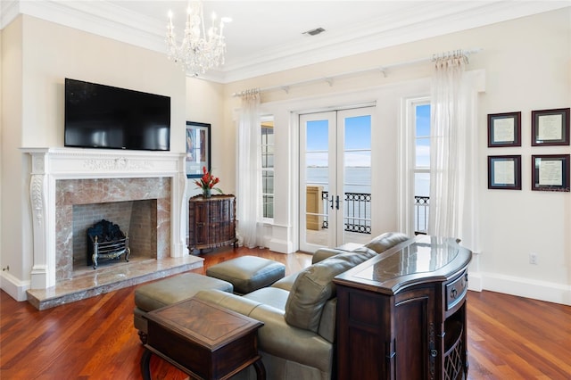309 Ringling Point Dr, Sarasota, FL 34234 - living room with french doors, a chandelier, dark wood-style flooring, ornamental molding, and a premium fireplace