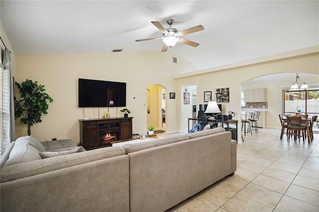 4649 72nd Ct E, Bradenton, FL 34203 - living room featuring arched walkways, a ceiling fan, vaulted ceiling, light tile patterned floors, and a lit fireplace