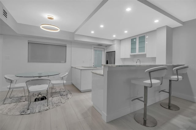 1150 Tarpon Center Dr Unit 1-C # 103, Venice, FL 34285 - kitchen with white cabinetry, stainless steel refrigerator with ice dispenser, a peninsula, glass insert cabinets, and recessed lighting