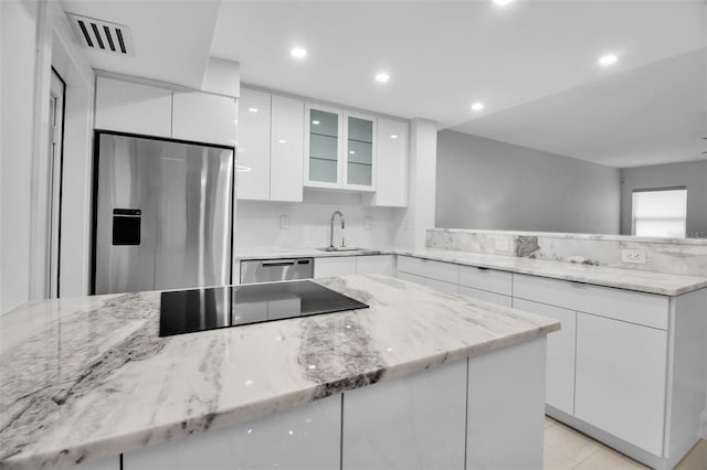 1150 Tarpon Center Dr Unit 1-C # 103, Venice, FL 34285 - kitchen with stainless steel appliances, modern cabinets, white cabinetry, a peninsula, and light stone countertops