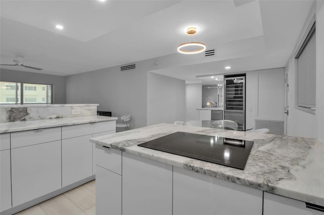 1150 Tarpon Center Dr Unit 1-C # 103, Venice, FL 34285 - kitchen with black electric cooktop, beverage cooler, white cabinetry, recessed lighting, and light stone counters