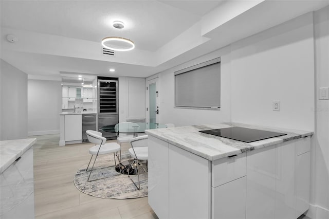 1150 Tarpon Center Dr Unit 1-C # 103, Venice, FL 34285 - kitchen featuring beverage cooler, black electric cooktop, white cabinetry, refrigerator, and recessed lighting
