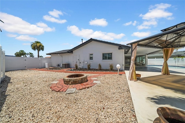 8001 13th Ave S, Saint Petersburg, FL 33707 - back of property with stucco siding, an outdoor fire pit, a fenced backyard, and a patio