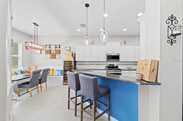 4654 Claremont Park Dr, Bradenton, FL 34211 - kitchen featuring stainless steel appliances, a kitchen bar, white cabinetry, hanging light fixtures, and recessed lighting