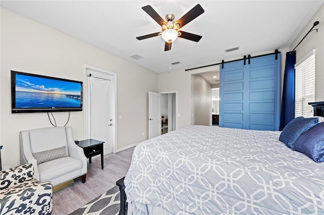 4654 Claremont Park Dr, Bradenton, FL 34211 - bedroom with a barn door, wood finished floors, and a ceiling fan