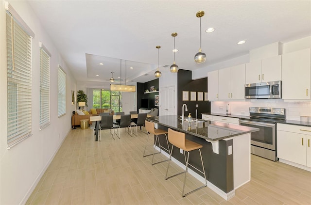 3602 Secret Stroll Dr, Sarasota, FL 34240 - kitchen featuring stainless steel appliances, a kitchen bar, a center island with sink, pendant lighting, and decorative backsplash